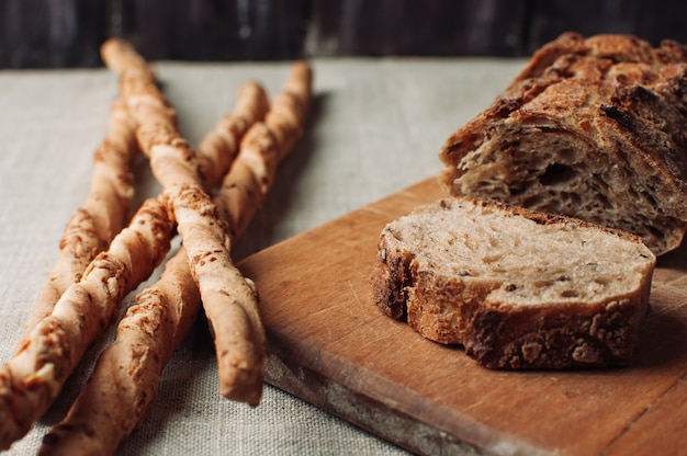 Dark yeast-free buckwheat bread in a cut lies on a cutting wooden board on a wooden table