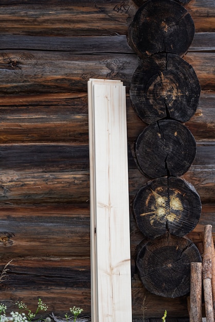 伝統的な木造住宅の暗い壁木造の壁に立てかけられた新鮮な板