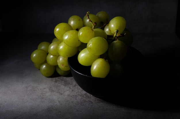 Darkfood style scene with a bunch of green grapes in a black basket