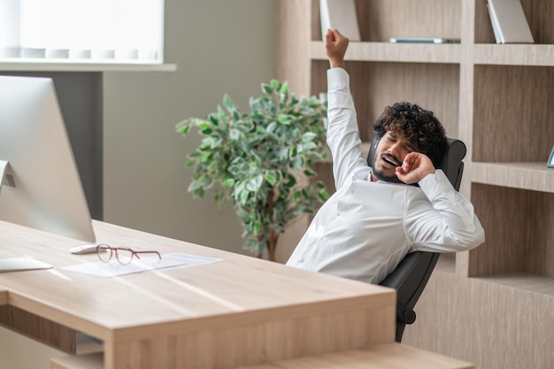 Darkhaired businessman feeling sleepy and stretching