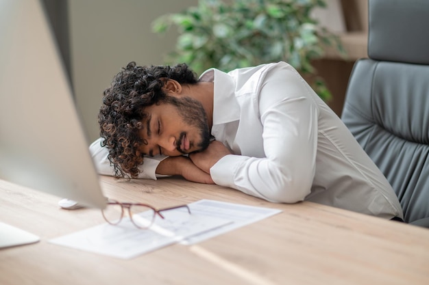 Darkhaired businessman sitting at the table and napping