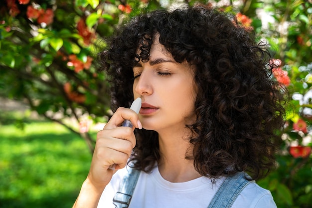 darkhaired young woman using nasal spray while having allergy symptoms