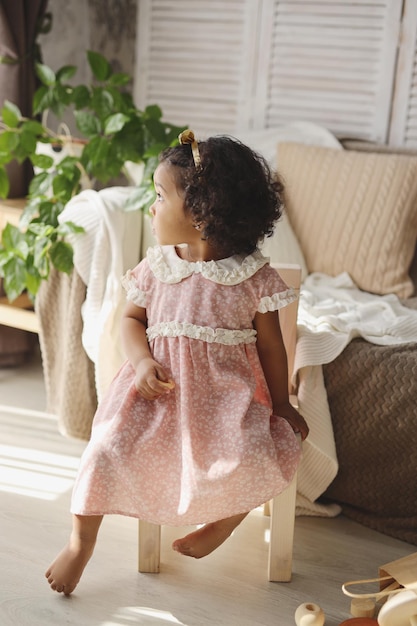 a darkskinned girl is sitting on a wooden chair at home the concept of environmental friendliness