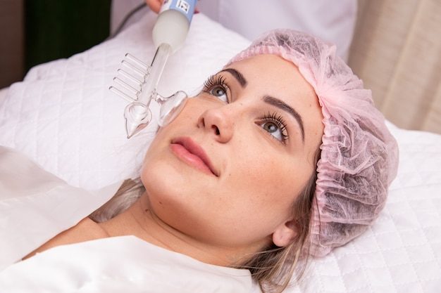 Darsonval cosmetica-apparaat. Procedure voor het reinigen van het gezicht. Salon huidverzorging behandeling. Professionele dermatologische hardware. Elektrische spa-apparatuur. Geneeskunde patiënt apparaat. acne verwijderen