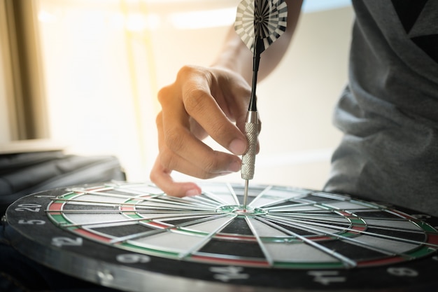 Стрелка дротика ударяя в центре цели dartboard используя как концепция дела.