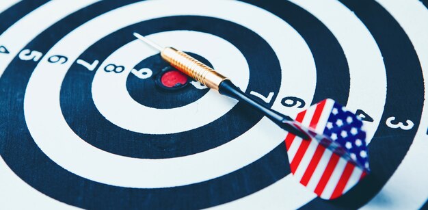 Dart arrow hitting in the target center of dartboard.