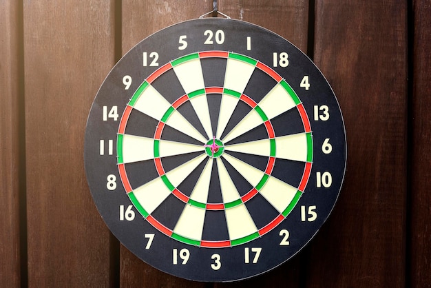 Dart arrow in the target center with wooden wall background