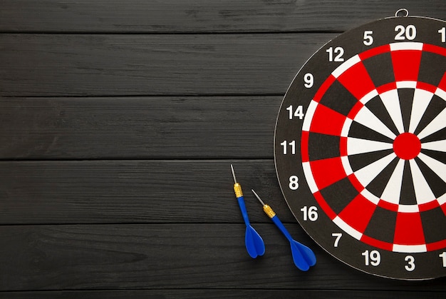 Photo dart board with red darts on black background. top view.