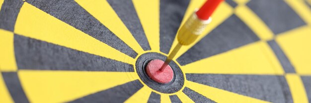 Dart in center of yellow-black dart board closeup