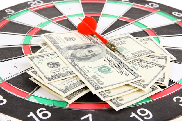 Dart on dartboard and money close up Concept of success