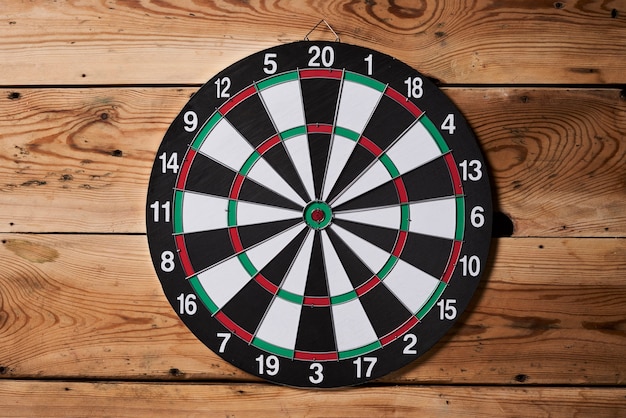 A dartboard hangs on the center of a wooden wall