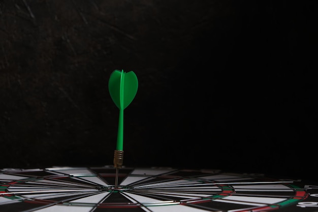 Dartboard with green dart stuck in center