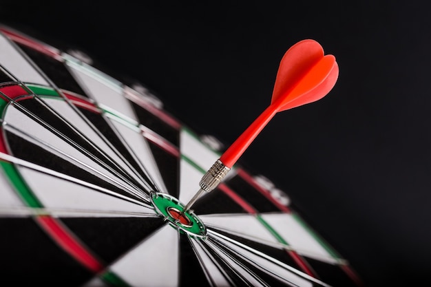 Darts board with red dart arrow on center of dartboard.