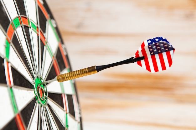 darts in the center of the target on a wooden background