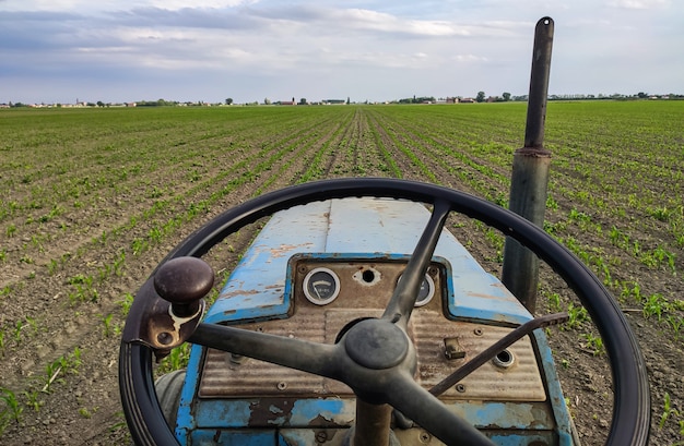 Dashboard van een oude roestige tractor in velden tijdens de lente