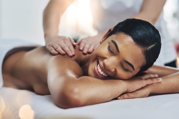 Dat voelt geweldig Foto van een ontspannen en vrolijke jonge vrouw die binnenshuis een massage krijgt in een spa