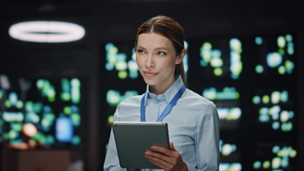 Foto donna che lavora in un data center su un tablet che guarda da lontano in un primo piano dell'ufficio