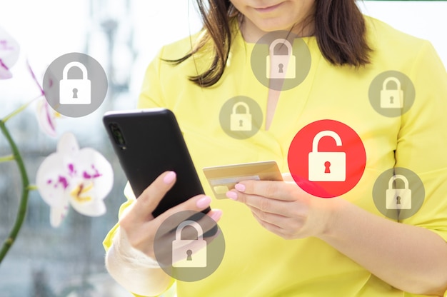 Data security when paying online with credit card. data\
protection and secure online payments. closeup view of woman hand\
using cellphone and laptop. virtual screen with icon of lock on\
it