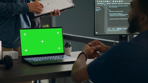 Database admins analyzing source code and greenscreen display on computer to develop software algorithm in busy space. cloud programers working with chromakey template isolated copyspace