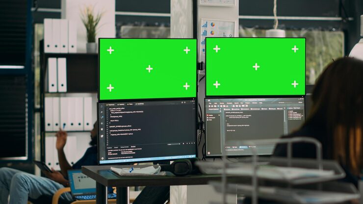 Photo database developer analyzing greenscreen display on multiple screens, working with server code on monitors. system engineer using isolated copyspace chromakey with mockup template in office.