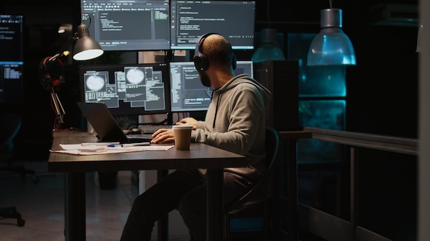 Database programmer writing html code on multiple screens, displaying cloud computing algorithm at night. Programming online network with coding language to develop new interface. Handheld shot.