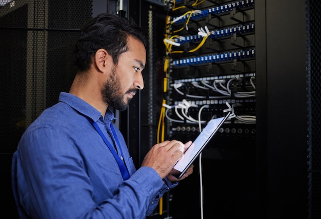 database tablet server room and engineer man looking at research for maintenance or software update at night cybersecurity it programmer or male coder with technology for networking in data center