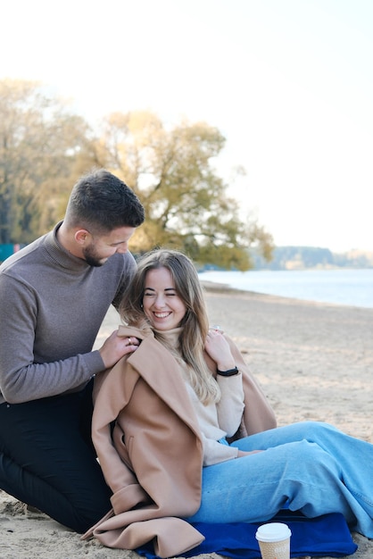 Date on the beach in the cold season The guy puts a coat on the girl's shoulders