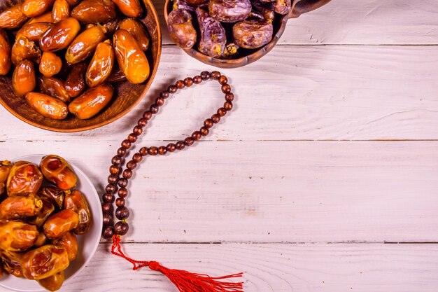 Date fruits and rosary on wooden table Top view