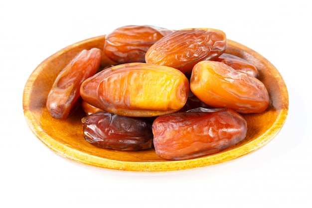 Date palm fruits in wooden bowl on white background