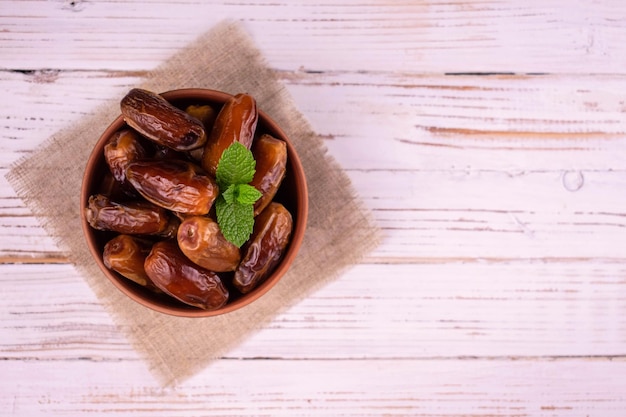 Dates in a bowl on a white wooden background.Copy space.