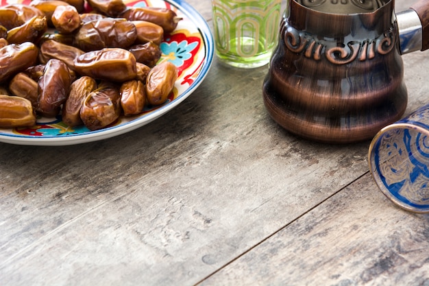 Dates food in plate and tea on wooden table, Copy space