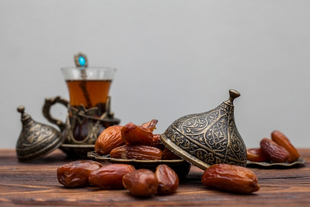 Photo dates fruit on plate with glass of tea