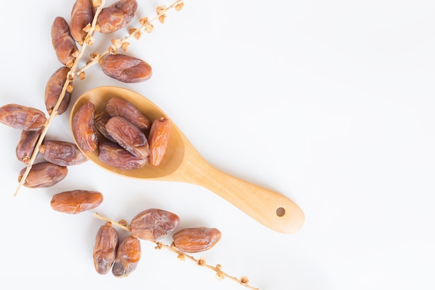 Dates fruit in wooden ladle on white background, Dried date palm fruits