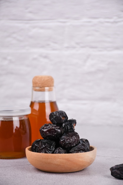Dates fruits in a wooden bowl and honey on white background whitespace Organic dried dates fruits
