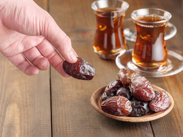 Dates with black tea on a wooden table. Traditional iftar food during Ramadan.