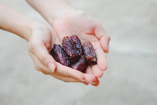 女性の手にある日付は、皮と一緒に丸ごと食べることができる乾燥した茶色の果物です