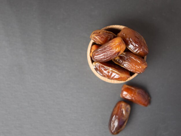 Dates in a wooden bowl on gray slate copy space