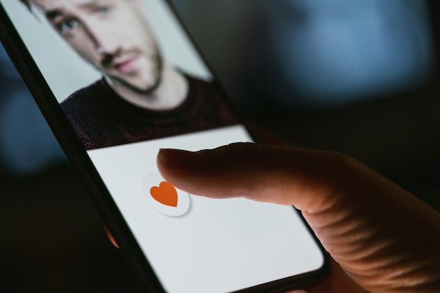 携帯電話の画面でアプリやサイトをデート。恋愛関係のサイトやアプリケーションでプロフィールをスワイプして好きな女性。スマートフォンを使用して愛、パートナー、ボーイフレンドを見つける独身女性。モックアップWebサイト。