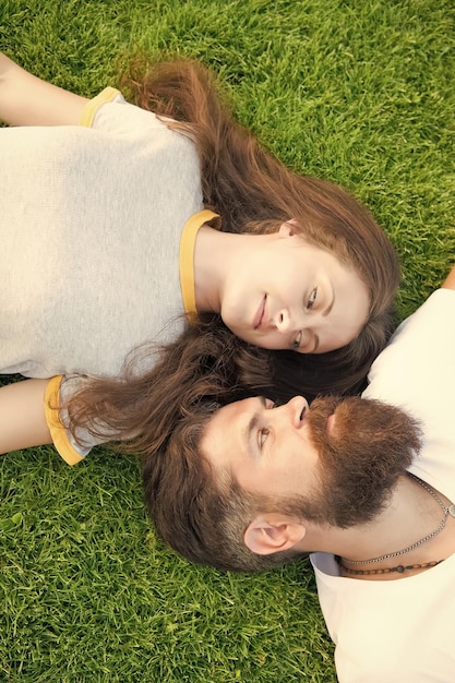 Dating concept bearded hipster and girl carefree Youth and freedom Closer to nature couple feel free couple lie on green grass man and woman relax outdoor dreaming concept Spring time