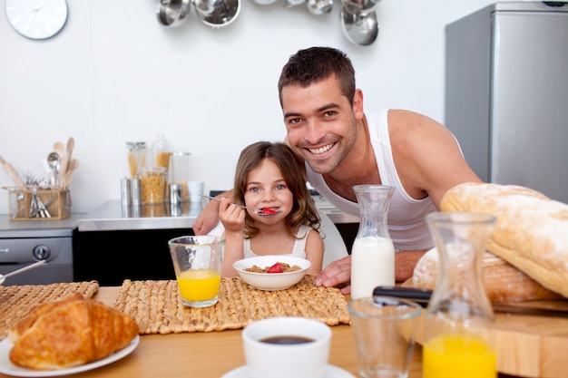 Daughter eating cereals and fruit in kitchen