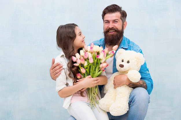 Figlia e padre festeggiano il compleanno. ragazza che saluta papà con la festa del papà. ritratto di famiglia felice con orsacchiotto. bouquet di fiori primaverili. festa della donna. preparare i tulipani per la festa della mamma.