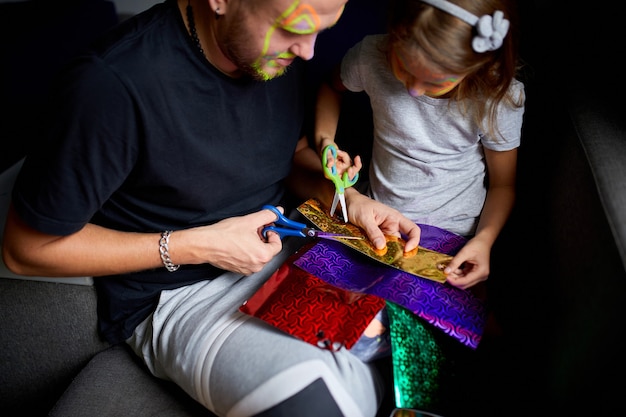 Daughter and father having fun making craft together at home on the sofa