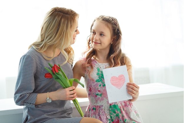 写真 娘は母親にチューリップの花束と自分の手で作ったポストカードを贈りました幸せな母性