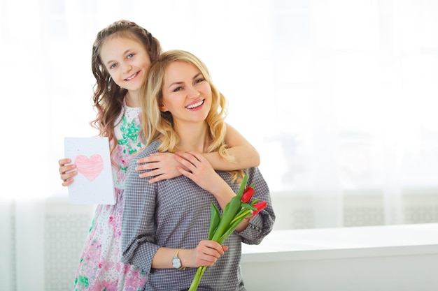 Daughter gave her mother a bouquet of tulips and a postcard made with her own hands