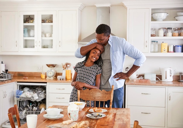 Daughter Helping Father To Clear Table After Family Meal