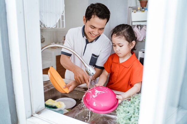 Daughter helping her father wash dishes