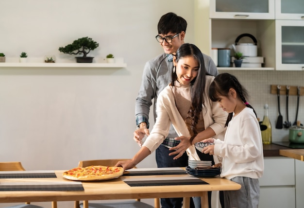 Daughter helping mom and dad to set up dining table before meal