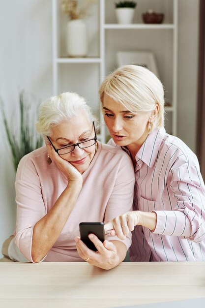 Photo daughter helping senior woman with smartphone