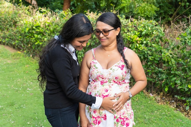 Дочь держит руки матери на беременном животе
