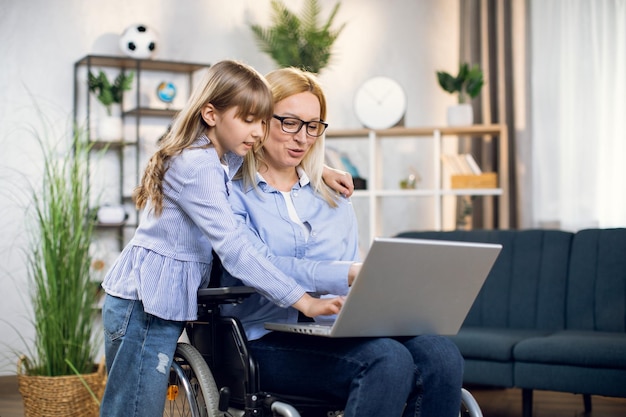 Daughter hugging mother in wheelchair with laptop